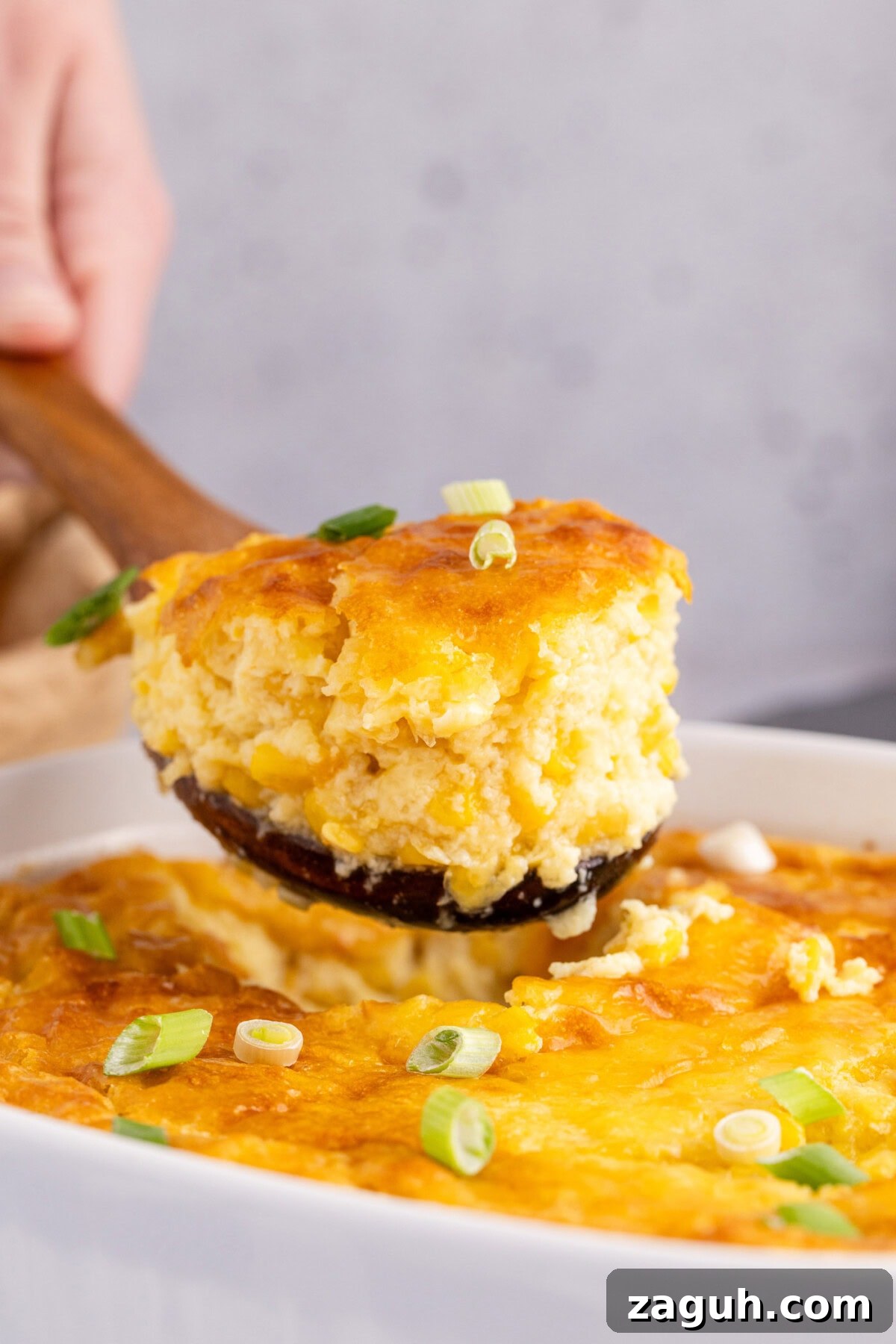 Creamy Southern-Style Corn Pudding Recipe 3 Scoop of Corn Pudding being lifted out of the baking dish