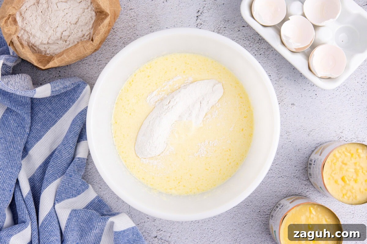 Creamy Southern-Style Corn Pudding Recipe 7 adding dry ingredients to wet ingredients in a mixing bowl