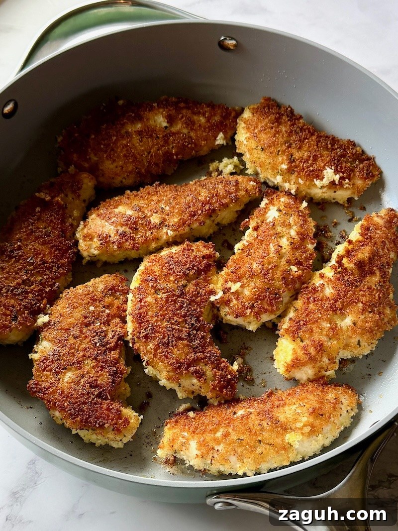 25-Minute Chicken Parmesan Recipe for Busy Family Dinners 9 Coated chicken tenders browned in a skillet.