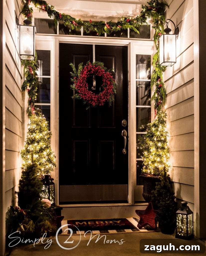 Classic Christmas Candlelight Tour You Have to See This Year 3 porch decorated for Christmas at night with mini trees, red berry wreath and lanterns
