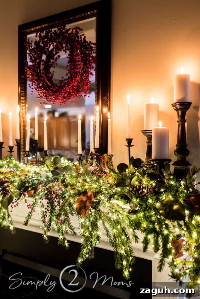 Classic Christmas Candlelight Tour You Have to See This Year 7 fireplace mantle decorated with lush Christmas garland embellished with red berries, eucalyptus leaves, and magnolia leaves with white tapers and pillar candles on black candlesticks