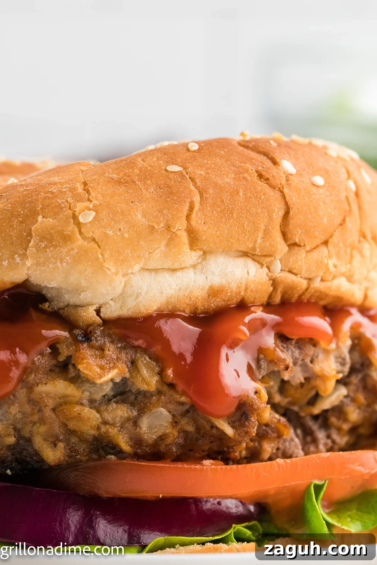 Meatloaf Burger on a plate layered with ketchup, slice tomatoes, red onion and lettuce
