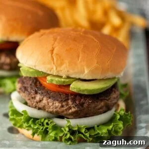 Hamburgers with lettuce, tomato and avocado on a tray.