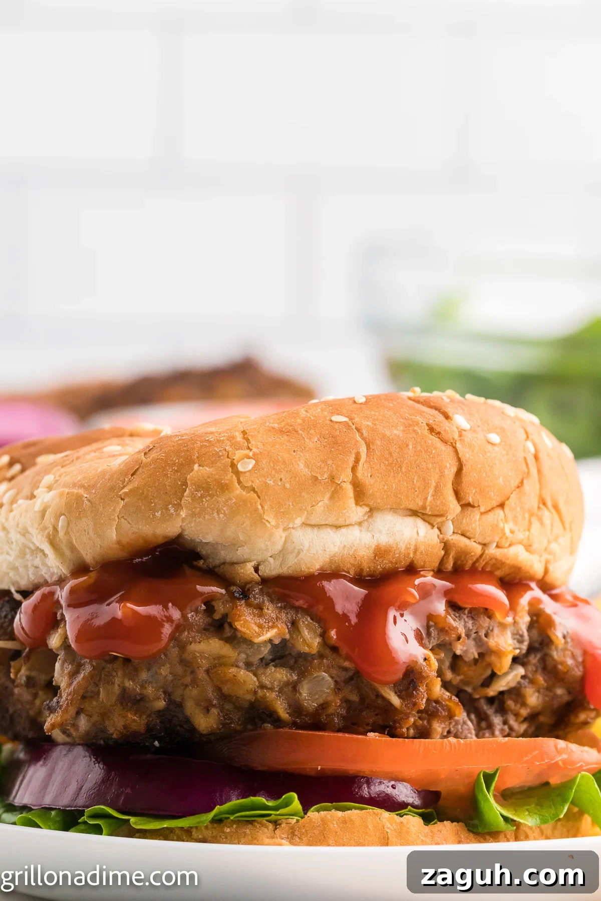 Meatloaf Burger on a plate layered with ketchup, slice tomatoes, and red onions