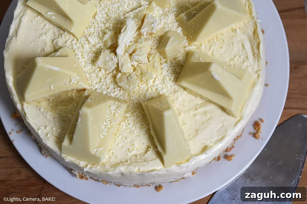 White Chocolate Toblerone Cheesecake Recipe — Creamy No-Bake Slice 5 Top view of half of the White Chocolate Toblerone Cheesecake on a white plate with a wood board background.
