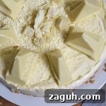 White Chocolate Toblerone Cheesecake Recipe — Creamy No-Bake Slice 8 Top view of half of the White Chocolate Toblerone Cheesecake on a white plate with a wood board background.