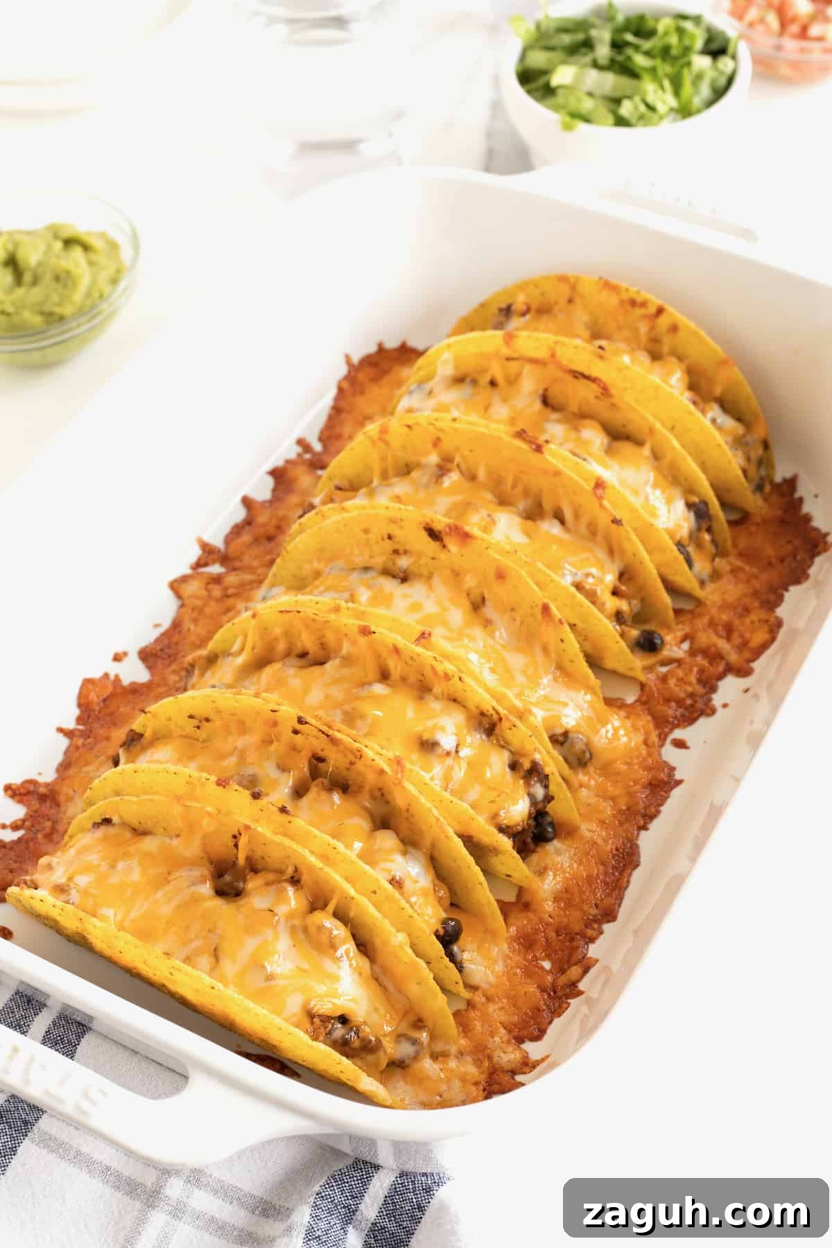 Authentic Mexican Fiesta Recipes for Your Party Menu 25 Seven tacos in a rimmed baking dish with melted cheese on top.