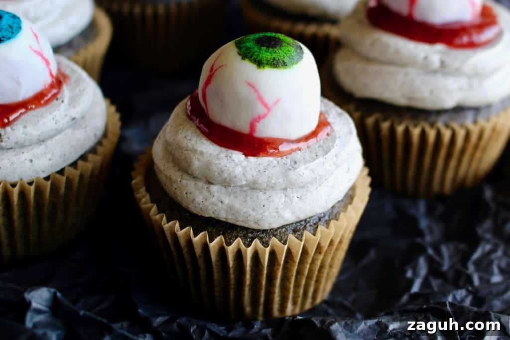 Halloween black sesame cupcakes are the perfect unique treat for an adult Halloween party! These Halloween eyeball cupcakes have a fluffy black sesame cake topped with black sesame buttercream frosting, topped with my Halloween white chocolate eyeballs! I added a spoonful of berry jam as fake blood, but I think mixing some black tahini with honey to make a spooky black goop would pair better in terms of taste. #halloween #halloweentreats #trickortreat #cupcake #cupcakes #blacksesame #kurogoma #sesame #cake #fluffy #black #spooky #creepy #dessert #halloweenparty #adult #eyeballs #whitechocolate #buttercream #frosting