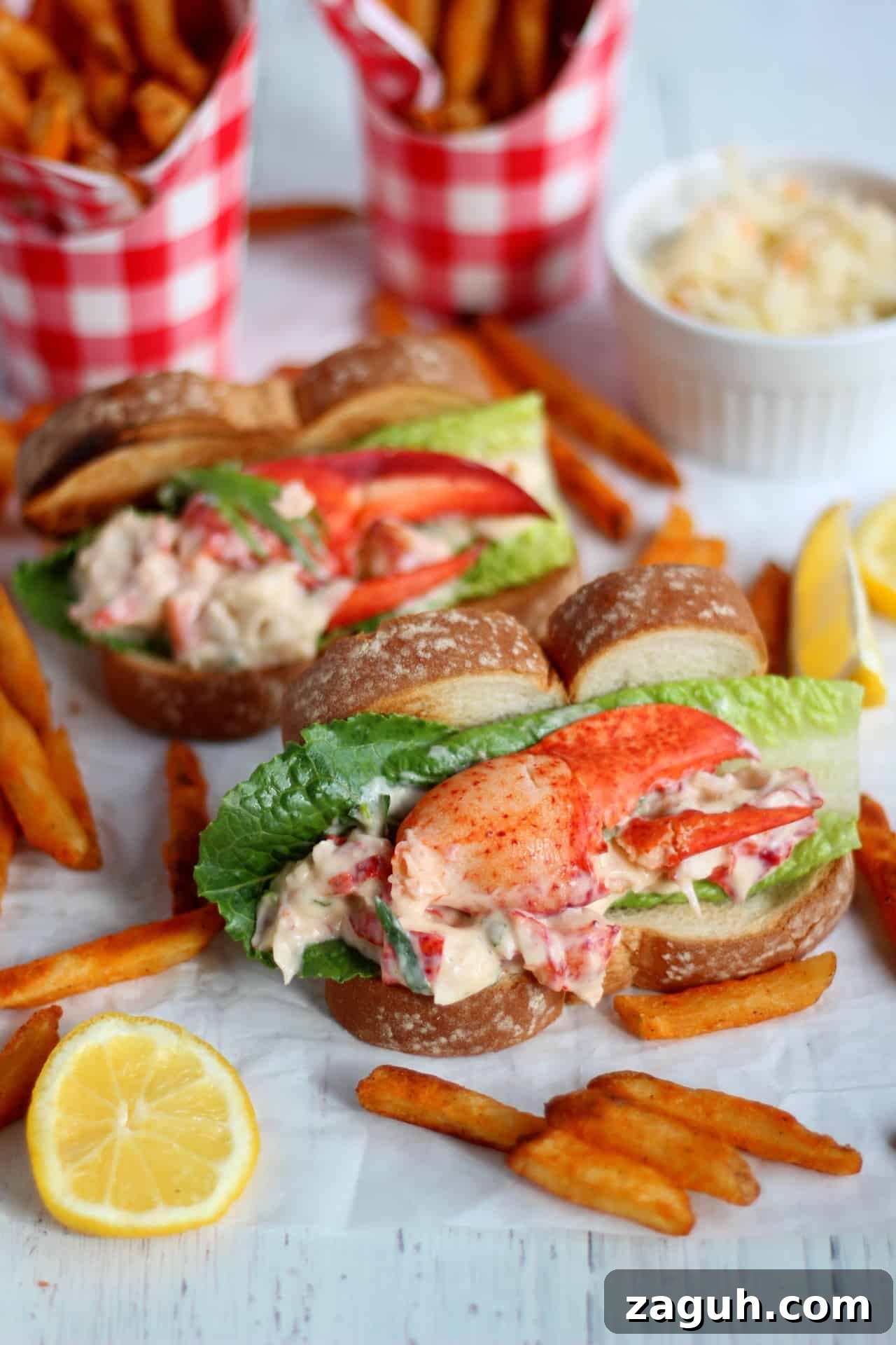 Classic New England Lobster Rolls: Authentic Recipe & Tips 7 filled hot dog buns with lobster mixture and salad. Sweet potato french fries laying around.