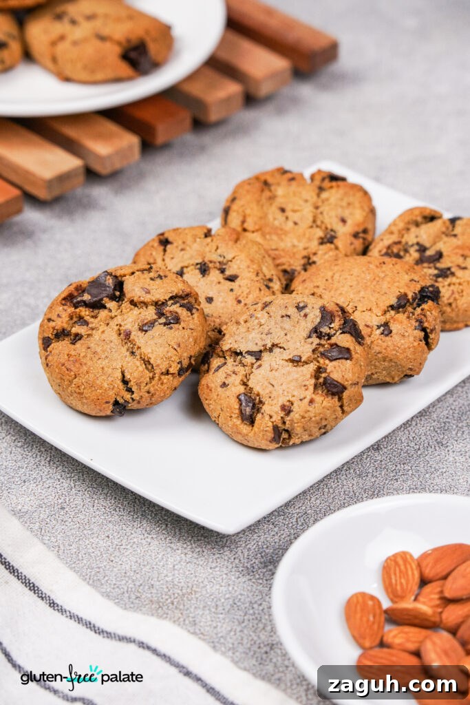 Almond Flour Chocolate Chip Cookie Recipe — Soft & Chewy</assistant 4 A plate of golden-brown paleo chocolate chip cookies with rich, melted chocolate chunks. A bowl of almonds is placed nearby.