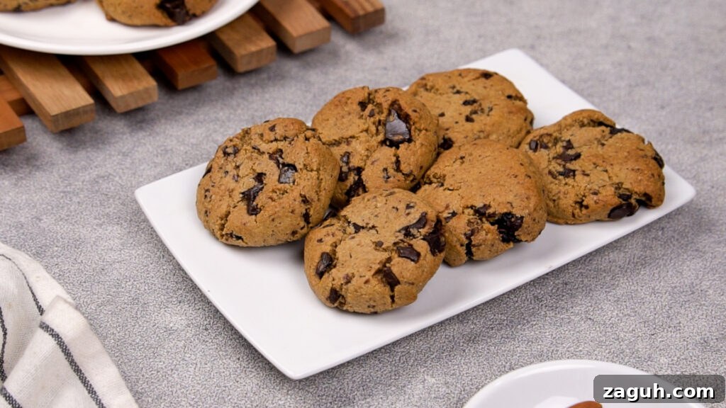 Almond Flour Chocolate Chip Cookie Recipe — Soft & Chewy</assistant 10 Freshly baked paleo chocolate chip cookies placed on a white plate, showing golden brown tops with melted chocolate chunks.