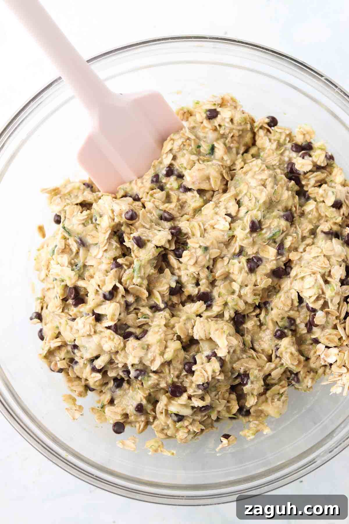 Moist Zucchini Oatmeal Bars with Cinnamon and Walnuts 2 Oatmeal, eggs, zucchini, chocolate chips, maple syrup and eggs all mixed in a bowl.