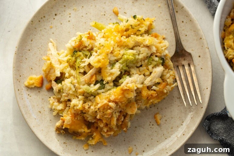 Simple Chicken, Broccoli and Rice Casserole Recipe 3 a serving of broccoli chicken rice casserole on a dinner plate with a fork sitting next to it