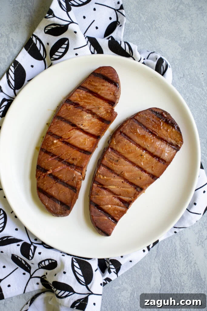 Grilled Tuna Steak Tacos with Crunchy Coleslaw 8 Grilled tuna steaks sitting on a white plate.