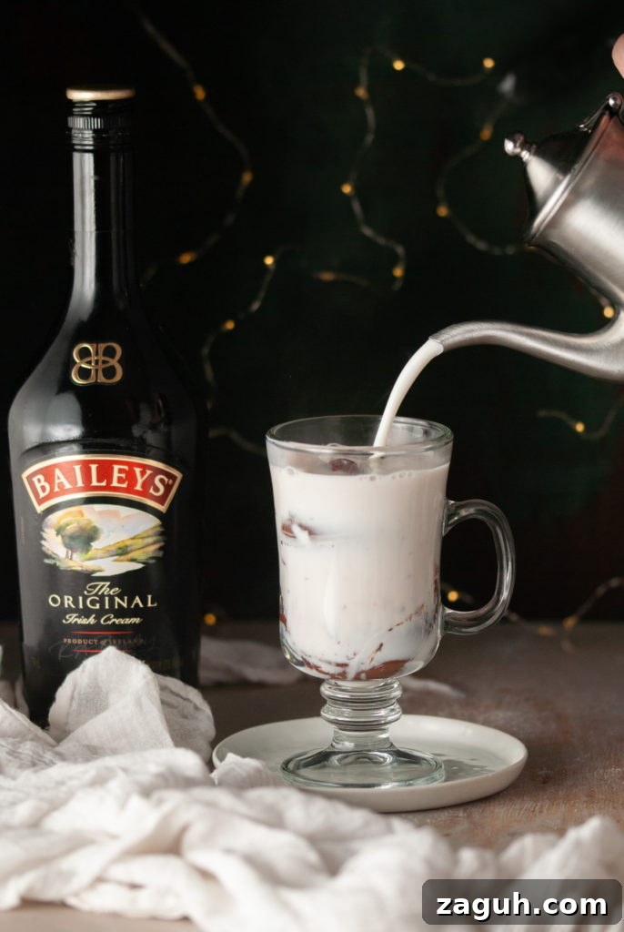 Baileys Hot Chocolate Bombs Recipe: Homemade Boozy Cocoa Surprises 16 Pouring hot milk over Baileys Hot Chocolate Bombs in a glass.
