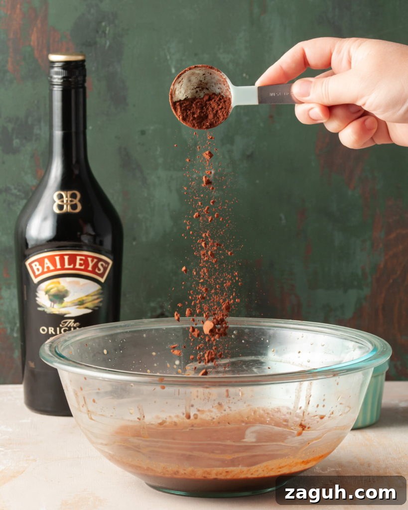Baileys Hot Chocolate Bombs Recipe: Homemade Boozy Cocoa Surprises 7 Adding cocoa powder to large mixing bowl with Baileys and melted chocolate.