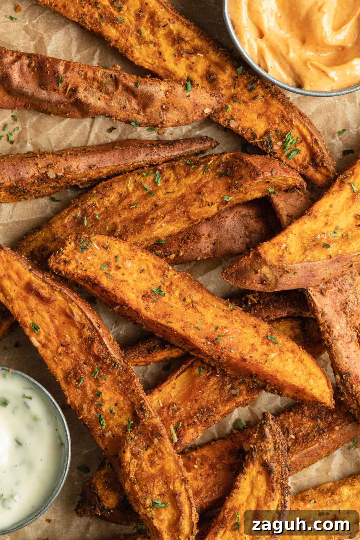 Crispy Air Fryer Sweet Potato Wedges Recipe 2 Overhead view of sweet potato wedge fries arranged on brown parchment paper.