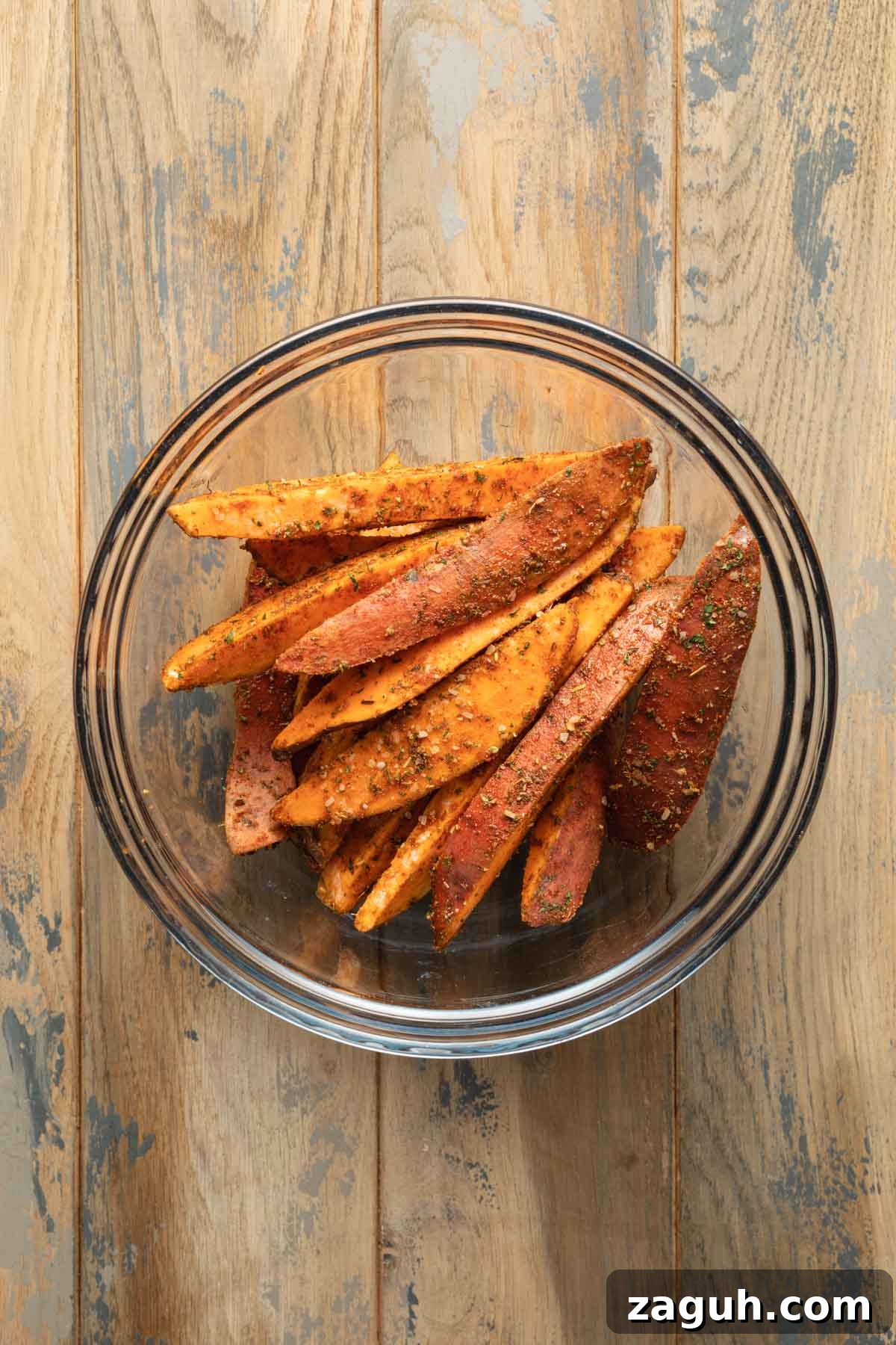 Crispy Air Fryer Sweet Potato Wedges Recipe 5 Seasoned sweet potato wedges in a glass bowl.