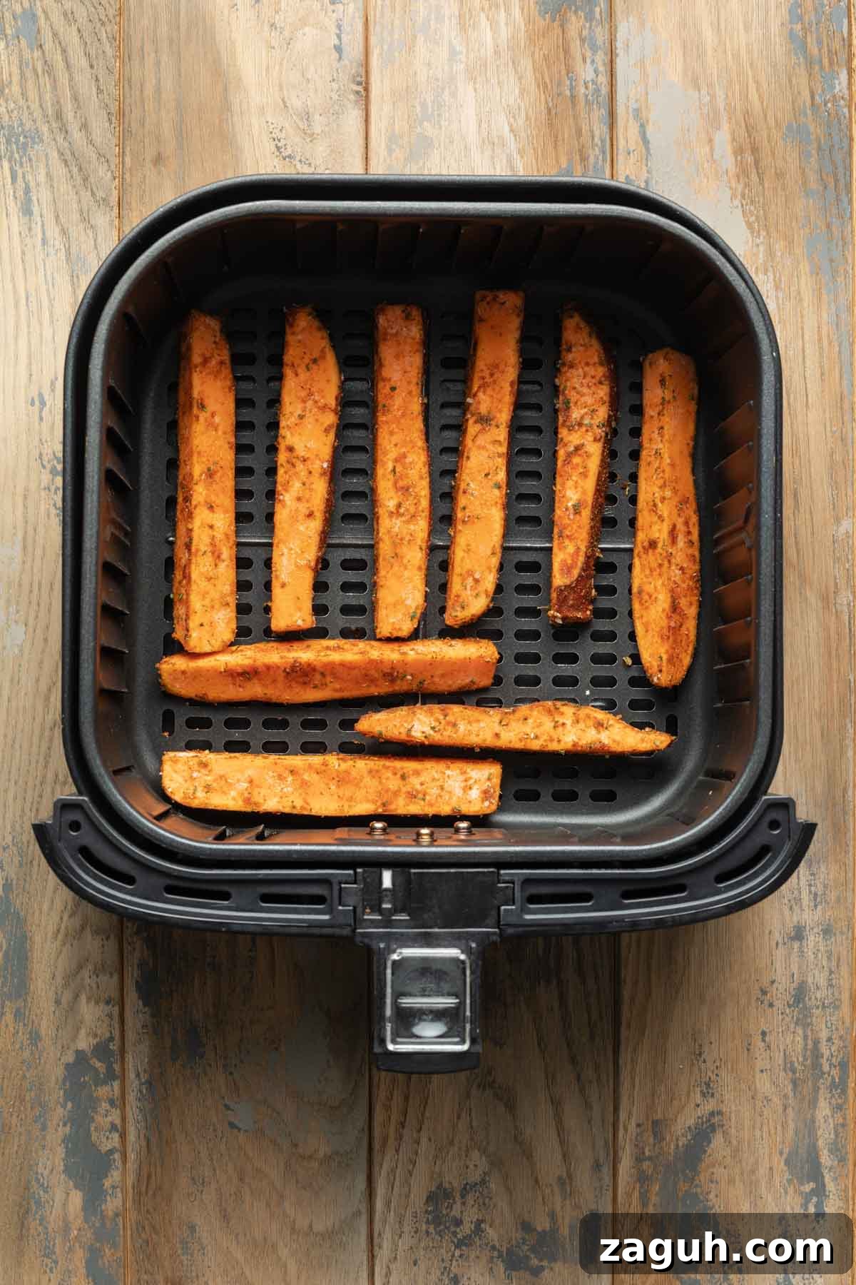 Crispy Air Fryer Sweet Potato Wedges Recipe 6 Seasoned sweet potato wedges arranged in a single layer in an air fryer basket.