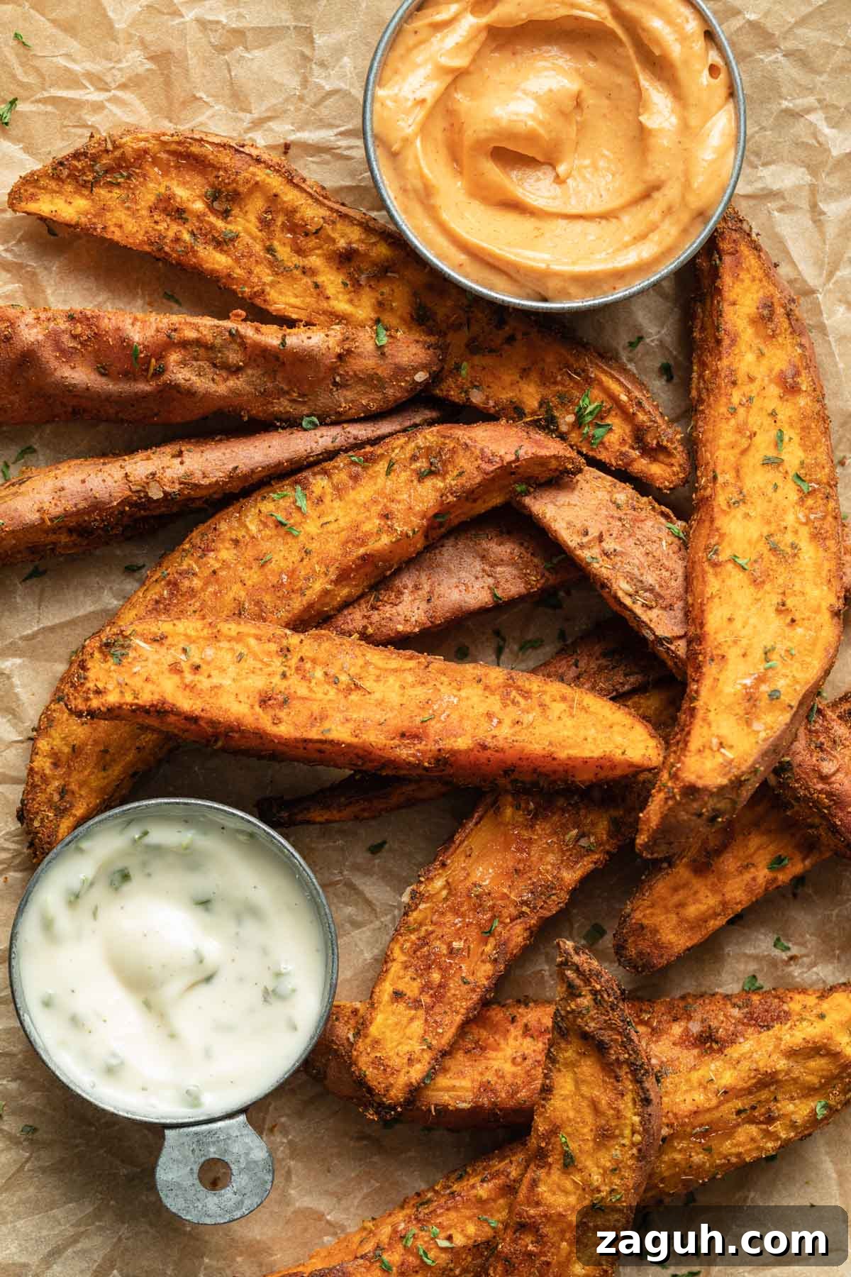 Crispy Air Fryer Sweet Potato Wedges Recipe 8 Air fryer sweet potato wedges arranged on parchment paper with a side of ranch dip.