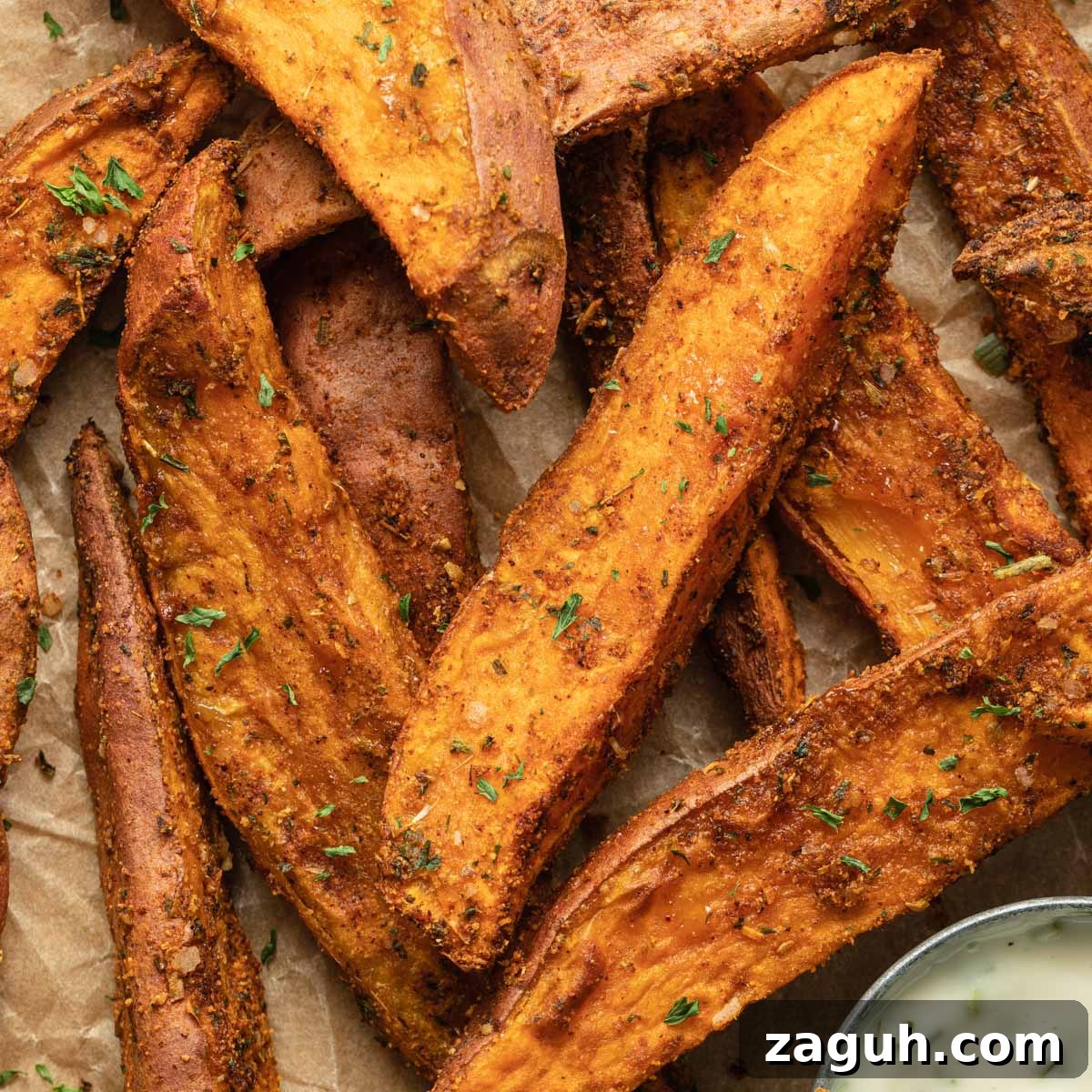 Crispy Air Fryer Sweet Potato Wedges Recipe 9 Close up view of air fryer sweet potato wedges arranged on brown parchment paper.