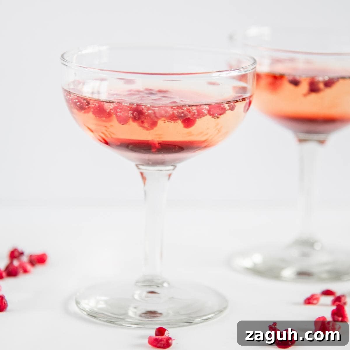 A pomegranate champagne cocktail garnished with pomegranate seeds.