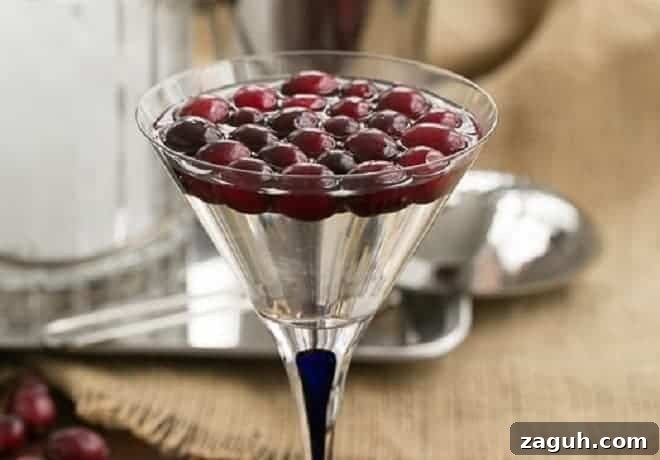 A white cosmopolitan cocktail garnished with cranberries.