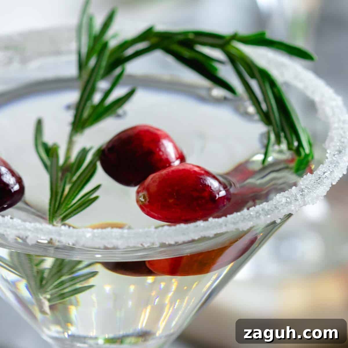 A winter white cosmo cocktail garnished with rosemary and cranberries.