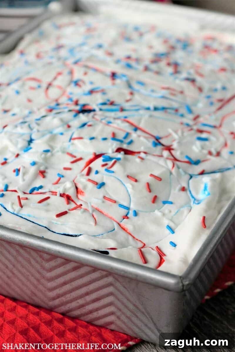 Red, White & Blue Poke Cake is topped with food coloring fireworks and sprinkles ... but wait until you cut a piece of this easy patriotic dessert!