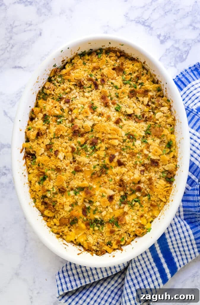 Creamy Corn Pudding Casserole Recipe for Comforting Sides 3 An overhead image of corn casserole in a pan with a blue and white checked towel next to it.