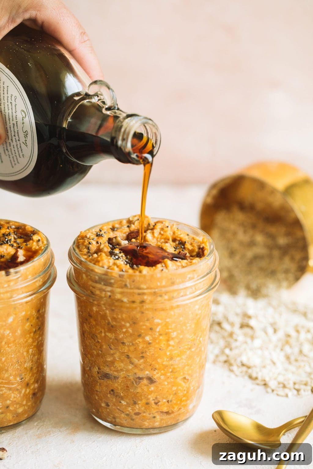 Creamy Pumpkin Overnight Oats Recipe for Fall Breakfast 6 maple syrup being poured on top of pumpkin spice overnight oats in glass jar