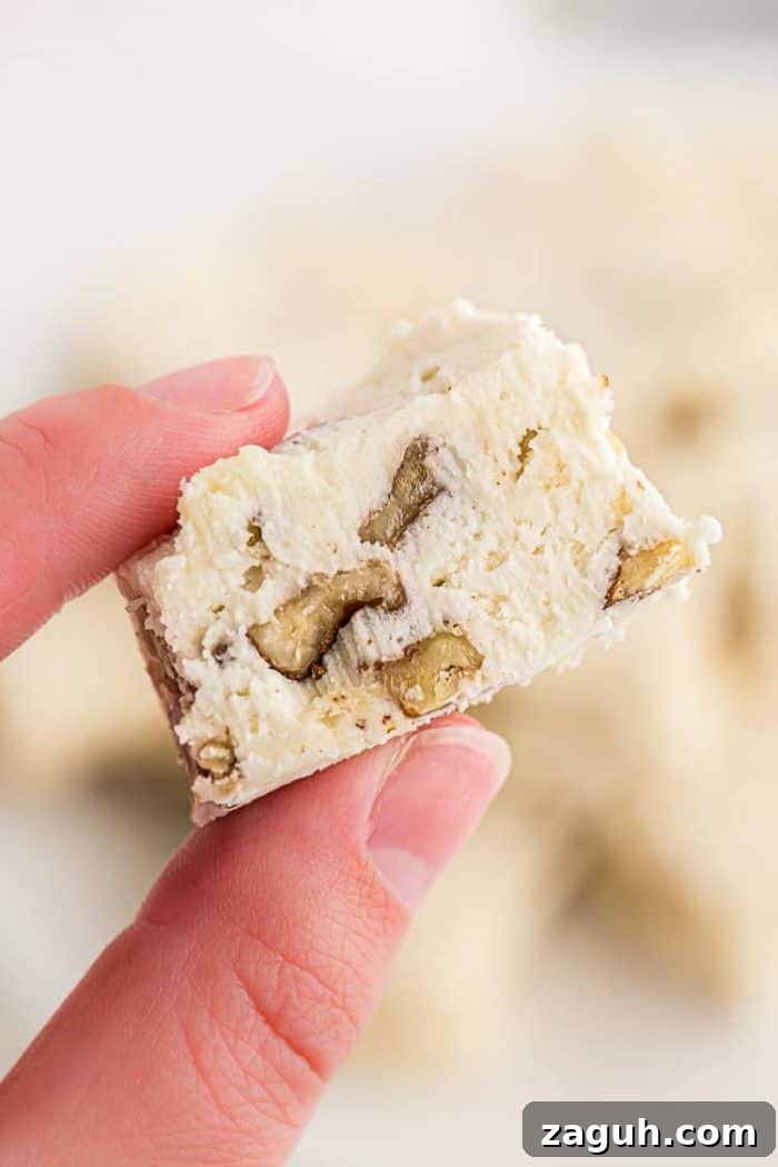 Keto White Chocolate Pecan Fudge — 2g Net Carbs Per Serving 8 hand holding up a zoomed in photo of keto fudge with pecans made from recipe