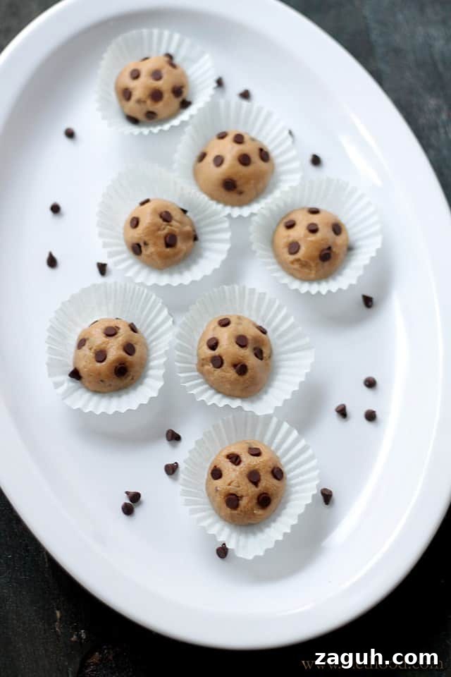 These Chocolate Peanut Butter Cookie Dough Balls taste just like classic chocolate chip cookie dough, but they’re no-bake, bite-sized, and quick to make. Cookie dough balls are topped with mini chocolate chips and served on a white platter.
