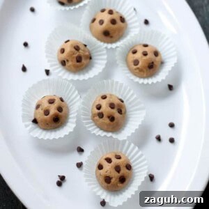 Chocolate Peanut Butter Cookie Dough Balls Recipe for No-Bake Treats 2 Cookie dough balls are topped with mini chocolate chips and served on a white platter.