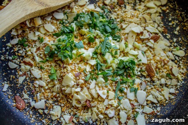 Make-Ahead Garlic Green Beans with Almonds and Crispy Breadcrumbs 11 toasted breadcrumbs, garlic, and almonds in a pan with wooden spoon.