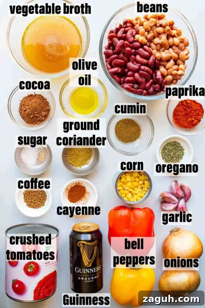 Guinness Vegan Chili Recipe: Rich, Hearty Stovetop Chili 3 top-down image of ingredients including vegetable broth, beans, cocoa, olive oil, paprika, sugar, coffee, crushed tomatoes, Guinness, cayenne, ground coriander, cumin, corn, bell peppers, onions, garlic and oregano.