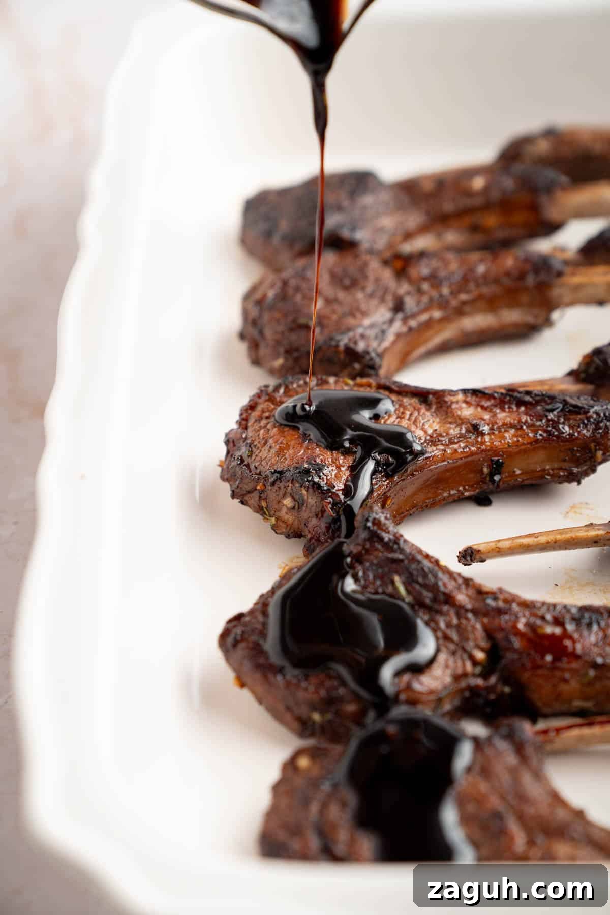 Balsamic-Glazed Oven-Baked Lamb Chops for Weeknight Dinner 8 A spoon pours the glaze over the lamb chops before broiling in the oven.
