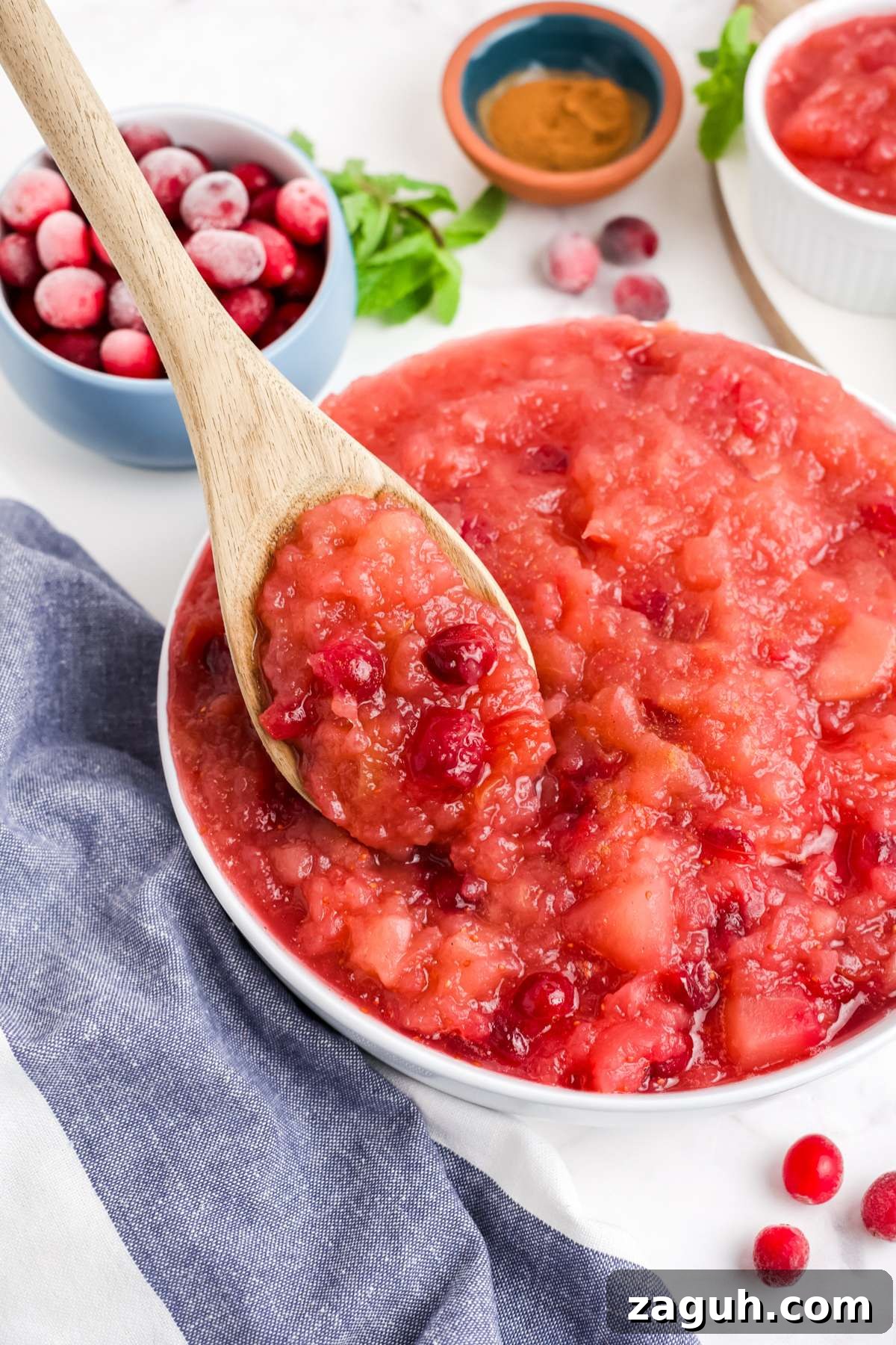 Cranberry Apple Sauce Recipe: Tangy Homemade Spread for Fall 2 Cranberry applesauce in a bowl with a spoon lifting up some of it from the bowl.