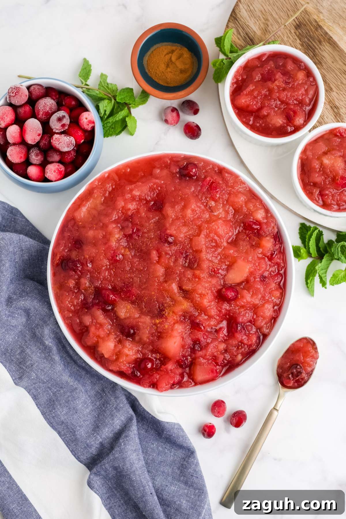 Cranberry Apple Sauce Recipe: Tangy Homemade Spread for Fall 8 Cranberry applesauce in a bowl on the table with a bowl of whole cranberries and a spoon to the side.