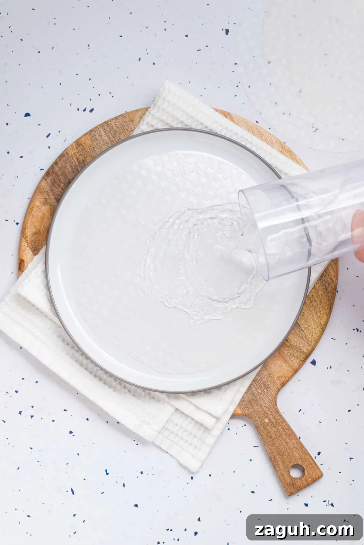 Overhead view of rice paper poured with water on a white plate.