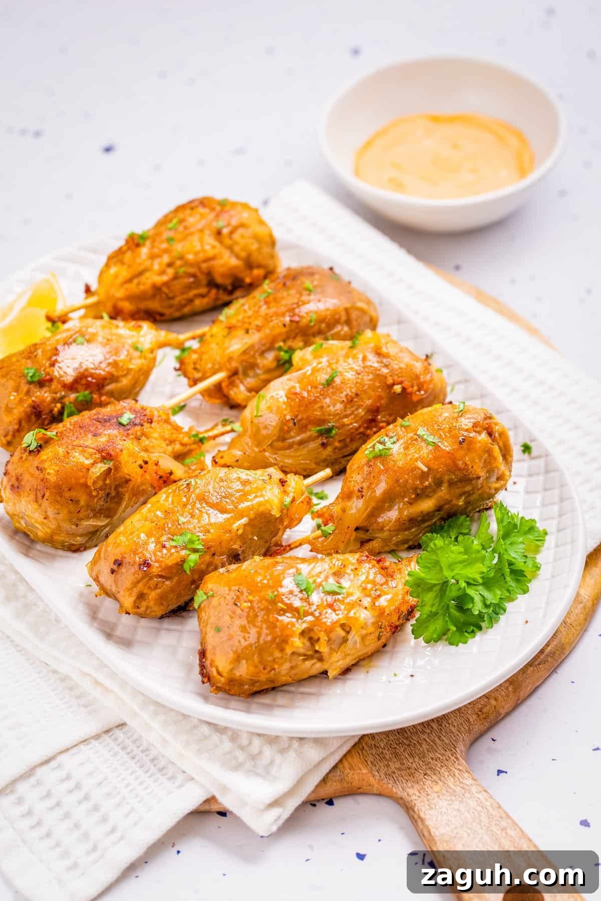 Overhead view of vegan drumsticks placed on a white plate with sriracha aioli on the side.