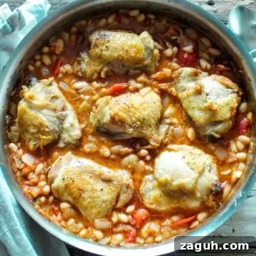 Overhead of chicken and white beans in skillet.