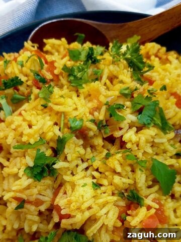 A serving dish of spicy Moroccan rice with a large wooden spoon.