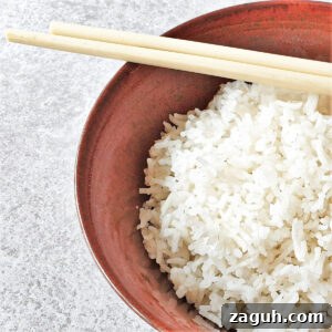A bowl of white rice with a pair of chopsticks.