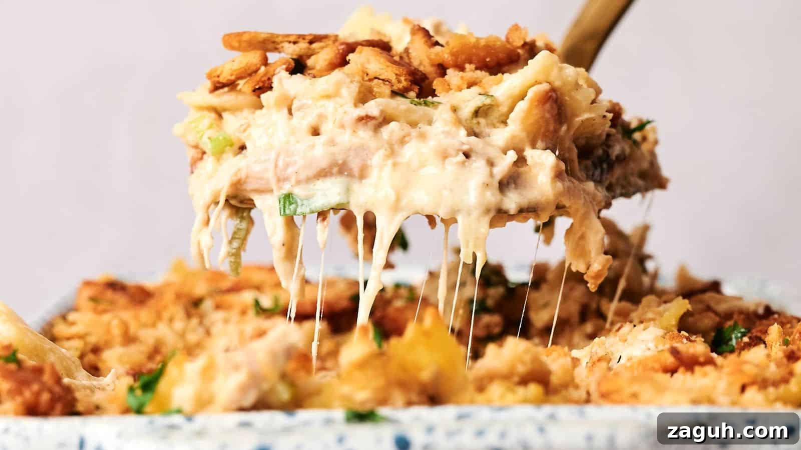 17 Show-Stopping Potluck Recipes That Steal the Spotlight 19 A serving spoon lifts a portion of creamy, baked casserole with a crunchy topping, revealing melted cheese.