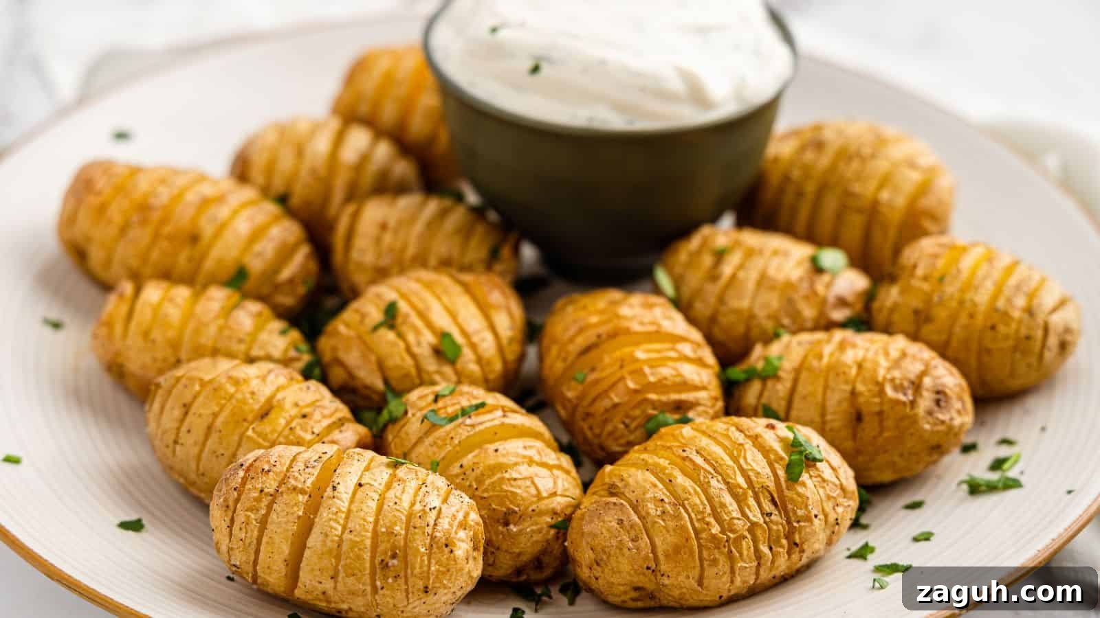 17 Show-Stopping Potluck Recipes That Steal the Spotlight 8 A plate of sliced, roasted baby potatoes is garnished with herbs. A small bowl of creamy sauce is placed in the center.