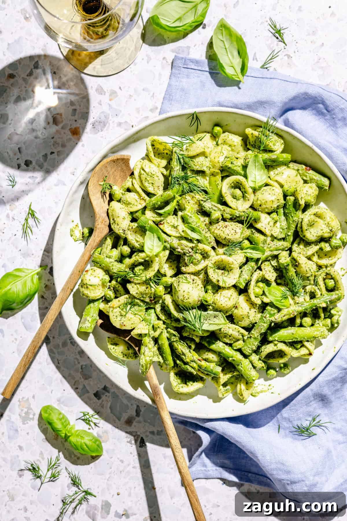 Green Goddess Pasta Salad in white serving bowl with two serving spoons.