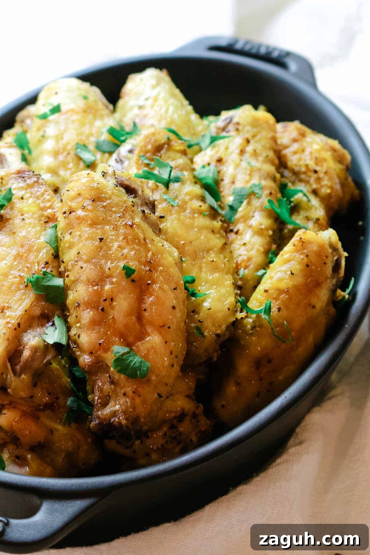 Crispy Baked Salt-and-Pepper Chicken Wings Recipe 10 chicken wings in black dish with parsley garnish.