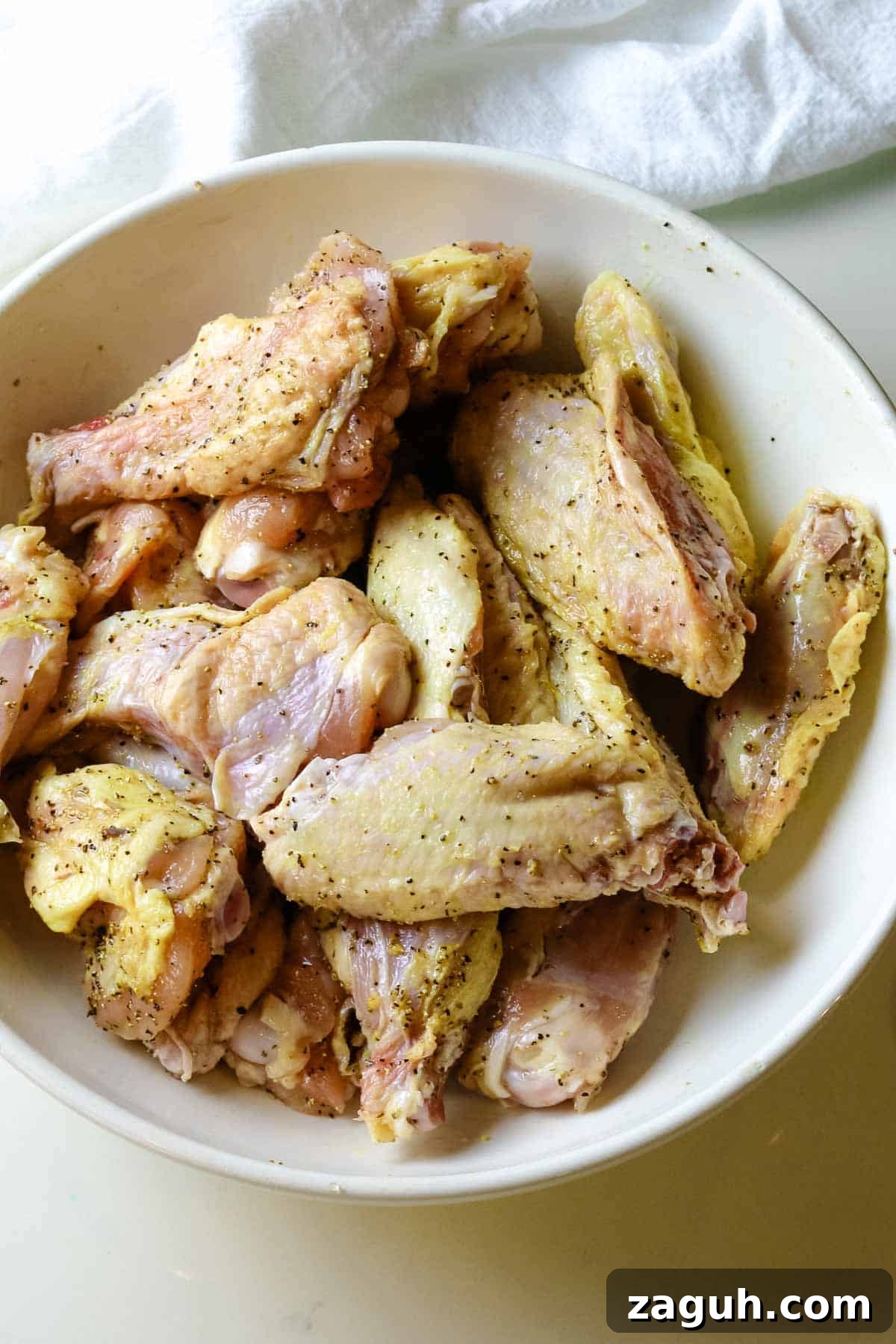 Crispy Baked Salt-and-Pepper Chicken Wings Recipe 5 seasoned chicken wings in a white bowl.