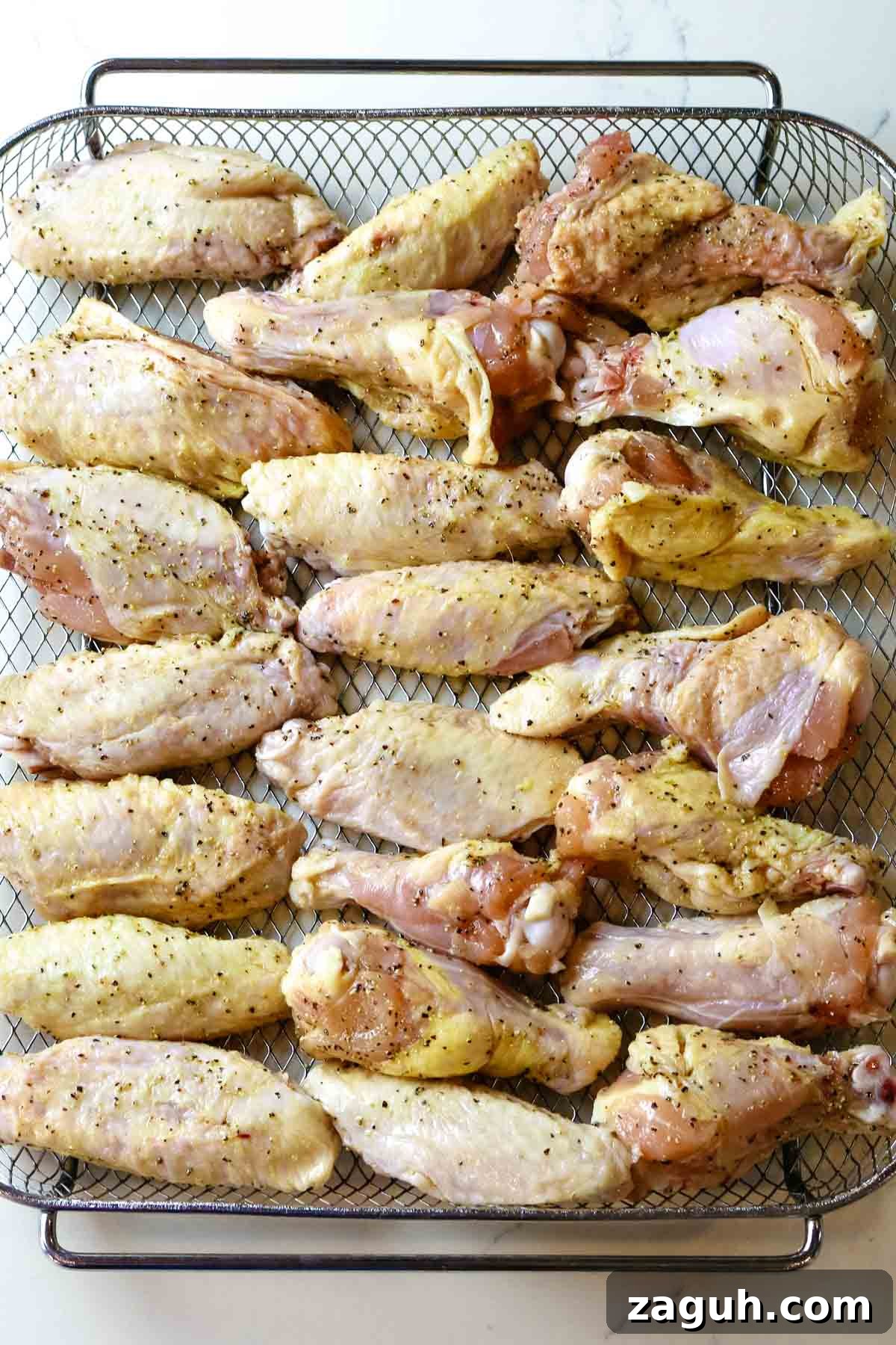 Crispy Baked Salt-and-Pepper Chicken Wings Recipe 6 chicken wings spread out in single layer on crisper tray.